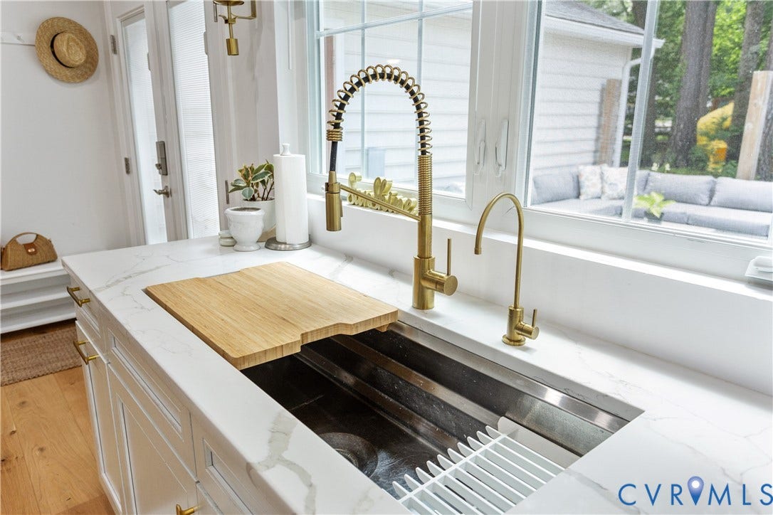 10100 Contessa Court, Glen Allen, VA 23060 Undermount stainless steel sink with a cutting board insert, brushed gold gooseneck faucet, and a separate filtered water dispenser, all set into a white countertop with subtle veining