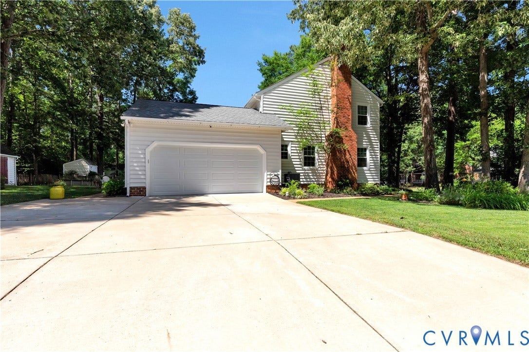 10100 Contessa Court, Glen Allen, VA 23060 Light-colored siding exterior featuring a two-car garage with white panel doors and a prominent brick chimney
