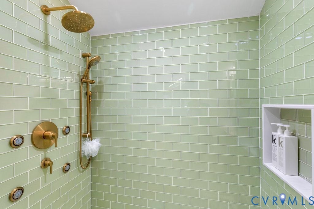 10100 Contessa Court, Glen Allen, VA 23060 Shower featuring light green subway tile, a rain shower head, a handheld shower fixture, and multiple body sprays, all with a brushed gold finish