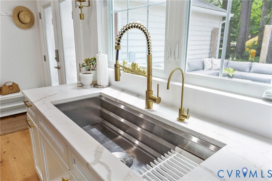 10100 Contessa Court, Glen Allen, VA 23060 Deep stainless steel sink with gold-tone fixtures, under a large window, set in white cabinetry with gold-tone hardware and white countertops