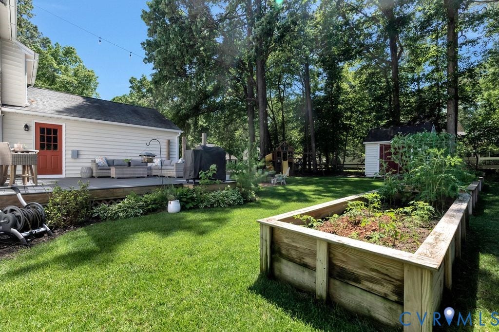 10100 Contessa Court, Glen Allen, VA 23060 Expansive backyard featuring a manicured lawn, a large raised garden bed, a wooden deck, mature trees, and a storage shed