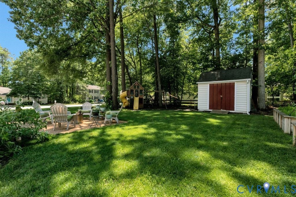 10100 Contessa Court, Glen Allen, VA 23060 Expansive lawn featuring a patio area, mature trees, and a detached storage shed with a dark green roof