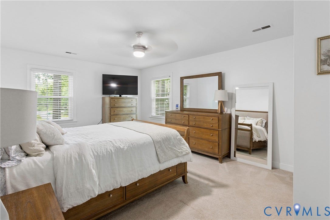 10100 Contessa Court, Glen Allen, VA 23060 Spacious bedroom featuring light-colored carpeting, multiple windows with blinds, a ceiling fan with integrated lighting, and a neutral wall palette