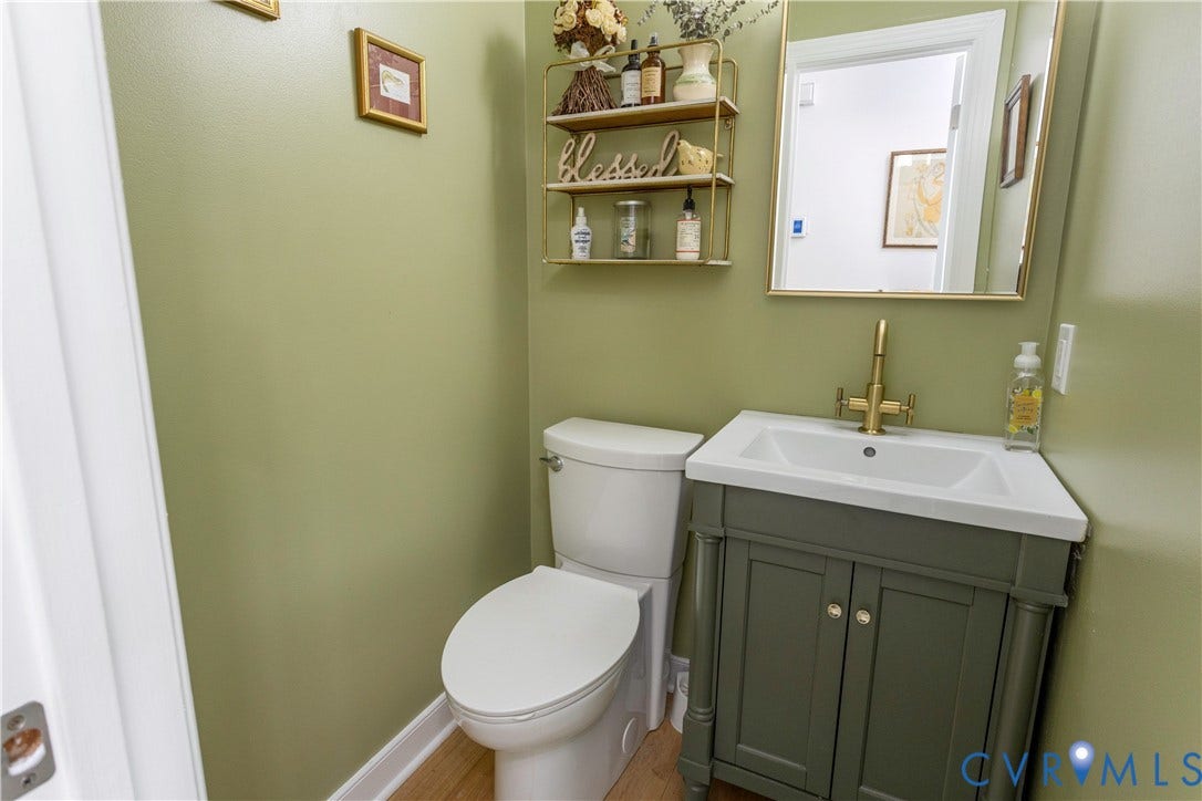 10100 Contessa Court, Glen Allen, VA 23060 Bathroom featuring a white toilet, a vanity with a dark green cabinet and white countertop, and a gold-framed mirror