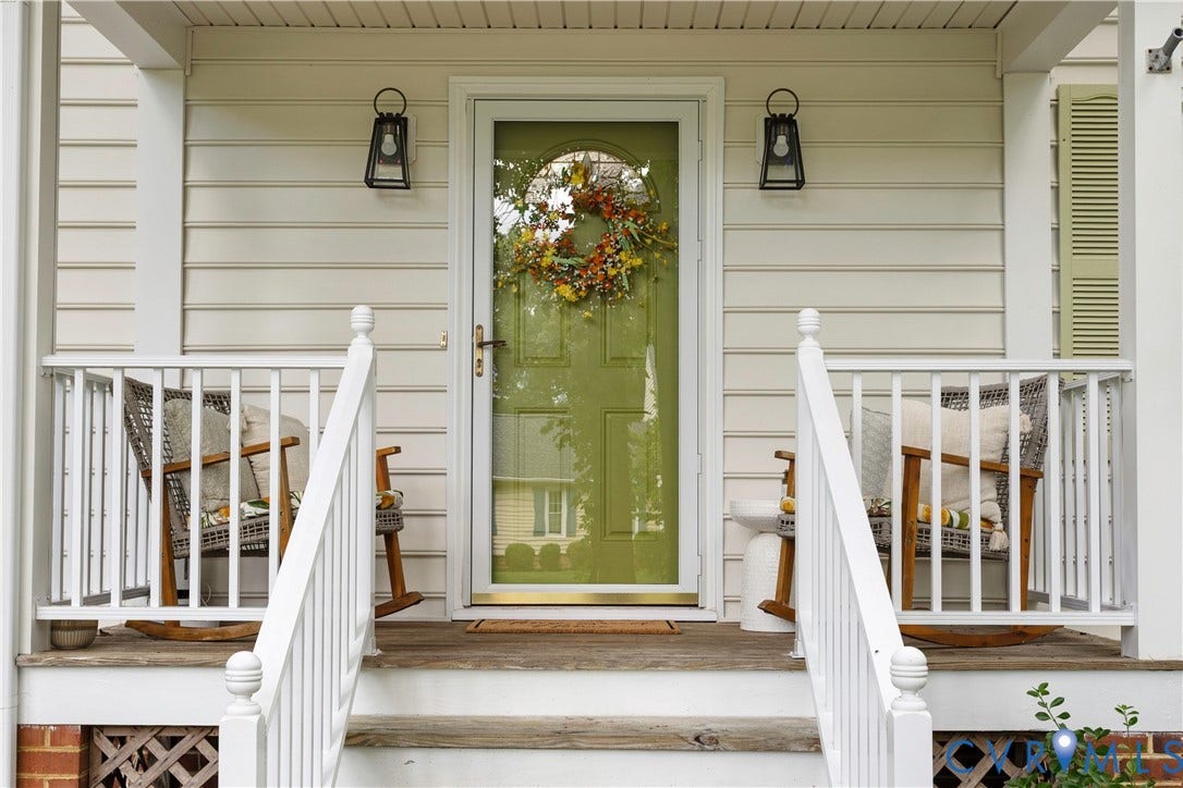 10100 Contessa Court, Glen Allen, VA 23060 Inviting front porch featuring a vibrant green entry door with a glass storm door, white siding, white railings, and two wall-mounted lantern-style light fixtures