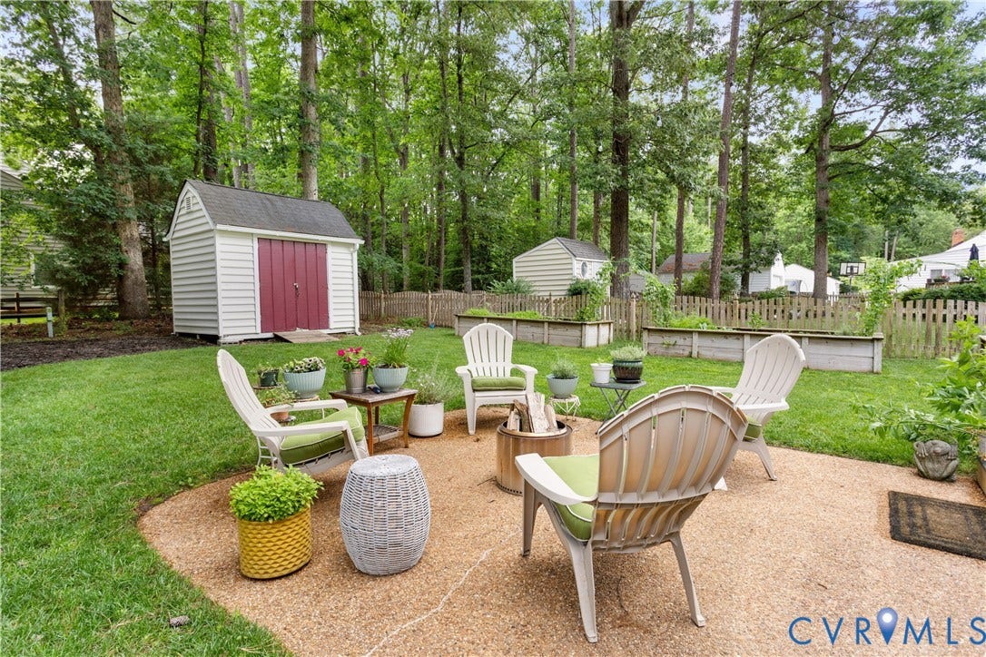 10100 Contessa Court, Glen Allen, VA 23060 Expansive backyard featuring a gravel patio, a storage shed with red doors, multiple raised garden beds, and mature surrounding trees