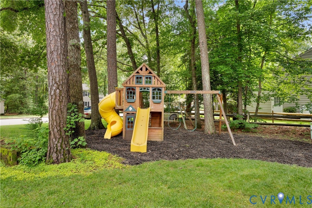 10100 Contessa Court, Glen Allen, VA 23060 Expansive backyard featuring mature trees, a manicured lawn, and a wooden playset with yellow slides and swings