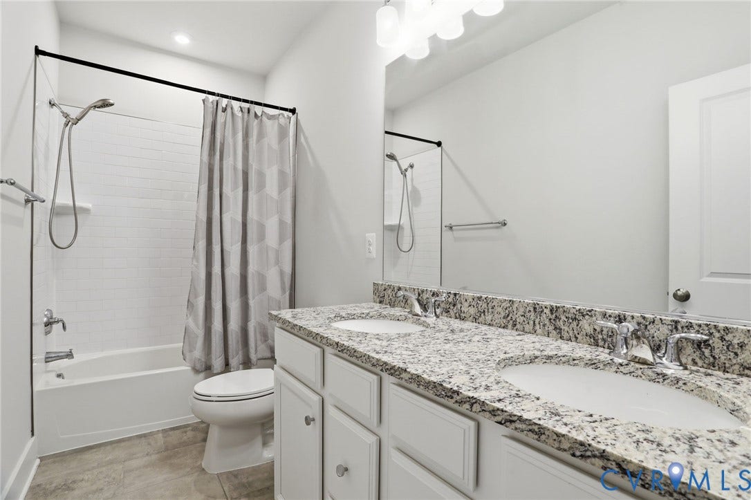 1121 N Lombardy Street, #B, Carver Square, Richmond, VA 23220 Hall Bath featuring a dual-sink vanity with a speckled countertop, white cabinetry, and polished chrome fixtures
