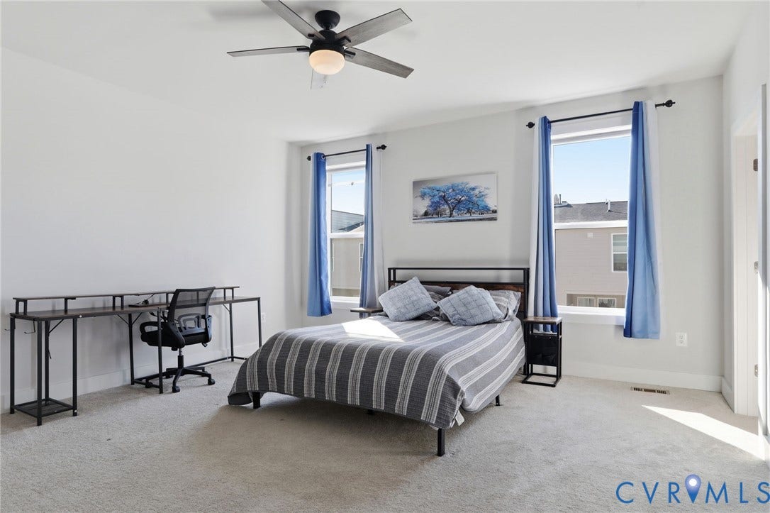 1121 N Lombardy Street, #B, Carver Square, Richmond, VA 23220 Carpeted Primary Suite featuring a ceiling fan with integrated lighting, white walls, and two large windows with dark curtain rods