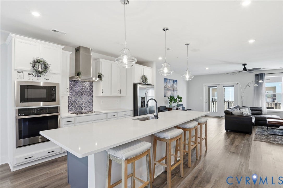 1121 N Lombardy Street, #B, Carver Square, Richmond, VA 23220 Open-concept kitchen featuring an expansive island with seating, quartz countertop, stainless steel appliances, white cabinetry, and wood-finish flooring
