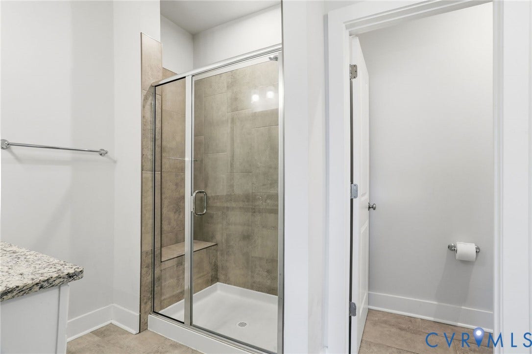 1121 N Lombardy Street, #B, Carver Square, Richmond, VA 23220 Shower enclosure featuring a built-in bench, clear glass panels, and tiled interior walls