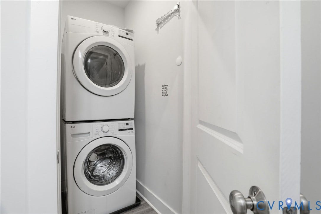 1121 N Lombardy Street, #B, Carver Square, Richmond, VA 23220 Compact laundry area featuring a stacked washer and dryer unit, light gray wall paint, white trim, and wood-finish flooring