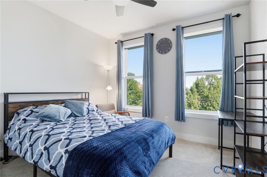 1121 N Lombardy Street, #B, Carver Square, Richmond, VA 23220 Bright bedroom featuring two large windows with tree-lined exterior, light-colored carpeting, a ceiling fan, and white walls