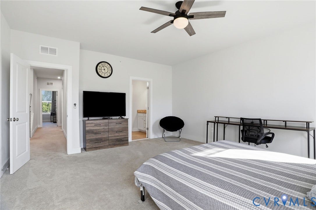 1121 N Lombardy Street, #B, Carver Square, Richmond, VA 23220 Carpeted Primary Suite featuring a ceiling fan with light fixture, white walls, and a recessed doorway providing access to an interior hallway