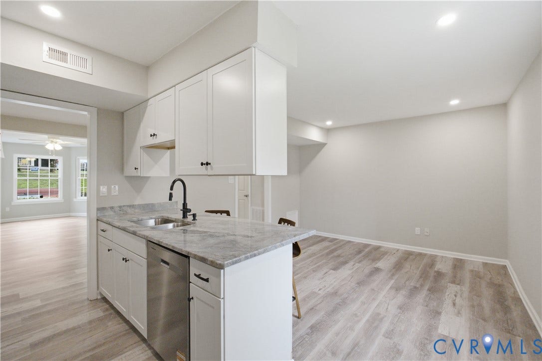 1304 Idlewood Avenue, Randolph, Richmond, VA 23220 Kitchen island featuring a stainless steel sink with a matte black faucet, granite-look countertop, and white shaker-style cabinetry with matte black hardware