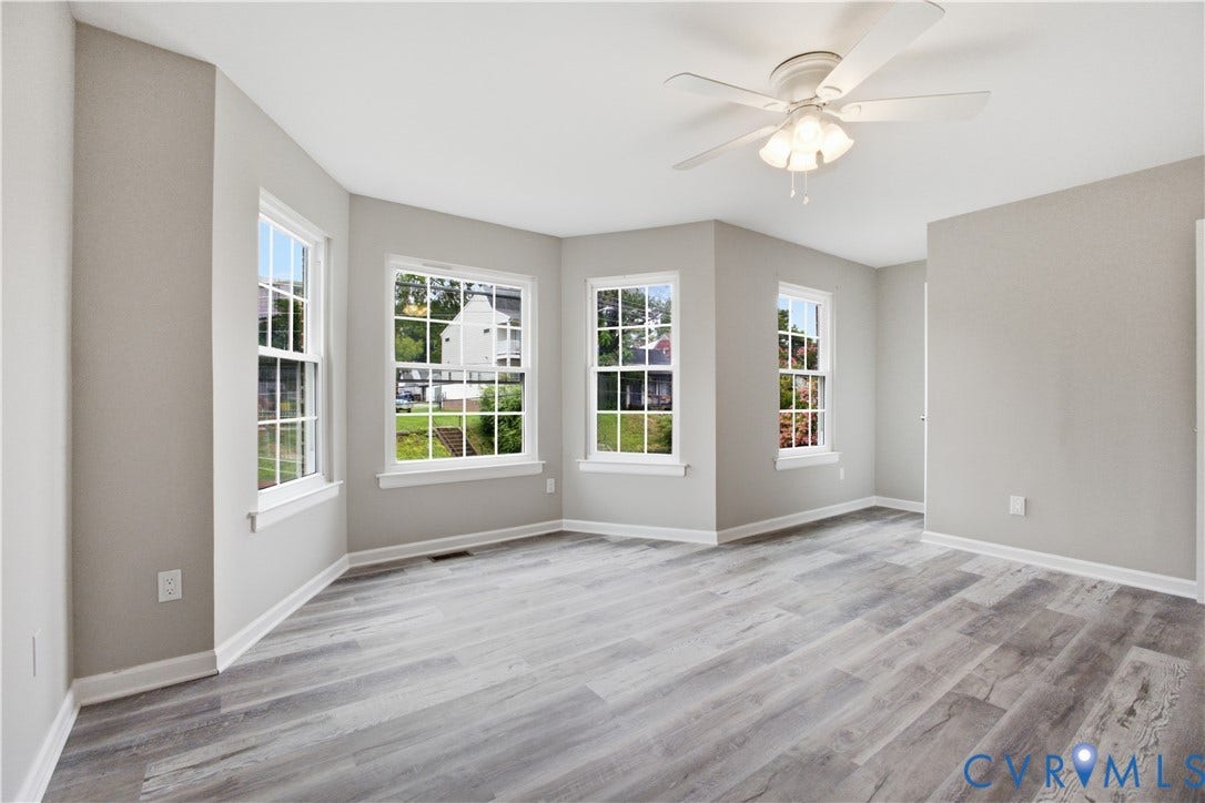 1304 Idlewood Avenue, Randolph, Richmond, VA 23220 Spacious room with light gray walls, white trim, wood-finish flooring, a ceiling fan with integrated lighting, and multiple windows