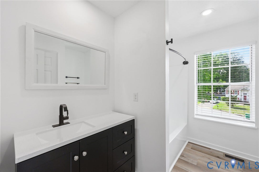 4217 Lipes Court, Glen Allen, VA 23223 Bathroom featuring a dark wood-finish vanity with a white countertop and integrated sink, a matte black single-handle faucet, a large framed mirror, a window with blinds, and wood-finish flooring