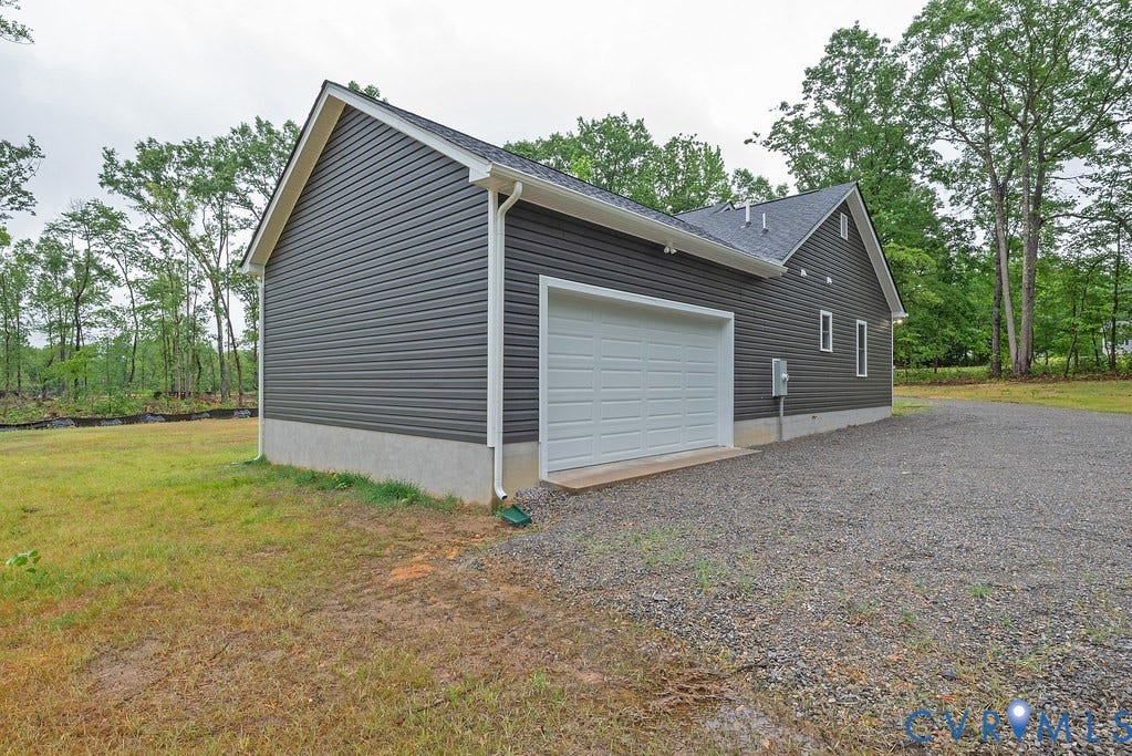 1220 Jefferson Highway, Moseley Estates, Louisa, VA 23093 Detached garage featuring dark gray horizontal siding, a white overhead door, and a gravel driveway