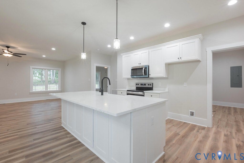 1220 Jefferson Highway, Moseley Estates, Louisa, VA 23093 Open-concept kitchen featuring a spacious island with a white countertop and a matte black faucet, white shaker-style cabinetry, and stainless steel appliances