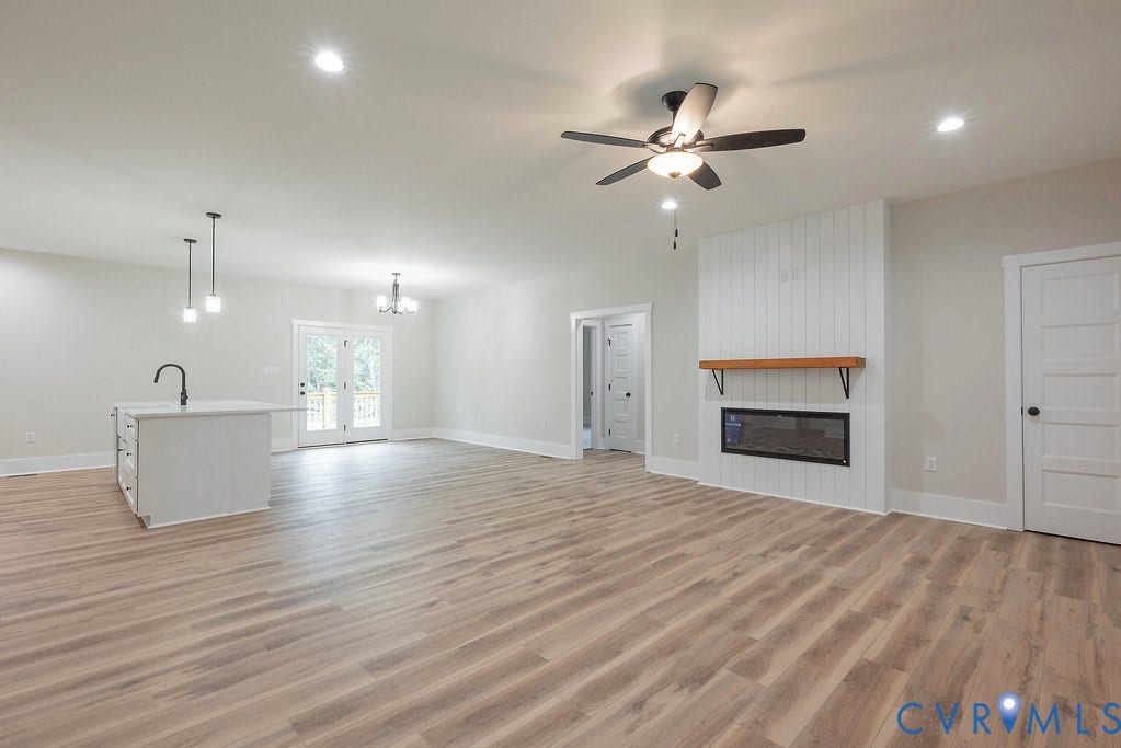 1220 Jefferson Highway, Moseley Estates, Louisa, VA 23093 Open-concept living area featuring wood-finish flooring, a contemporary fireplace with a wood mantel, and an island with a gooseneck faucet