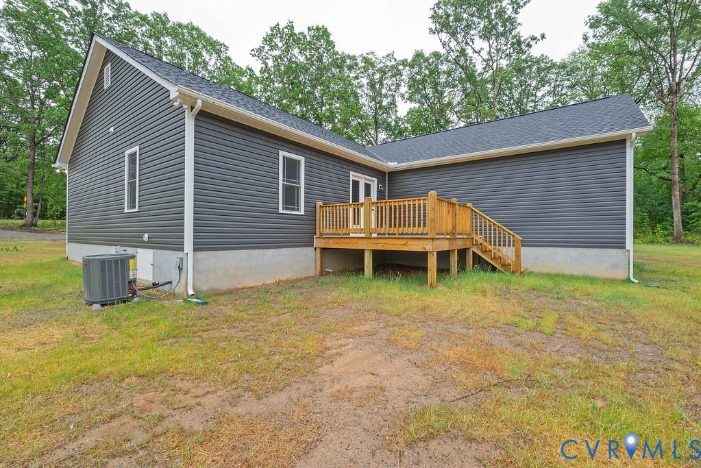 1220 Jefferson Highway, Moseley Estates, Louisa, VA 23093 Exterior featuring dark gray vinyl siding, white trim, a dark gray shingled roof, a wooden deck with railing and steps, and a visible HVAC unit
