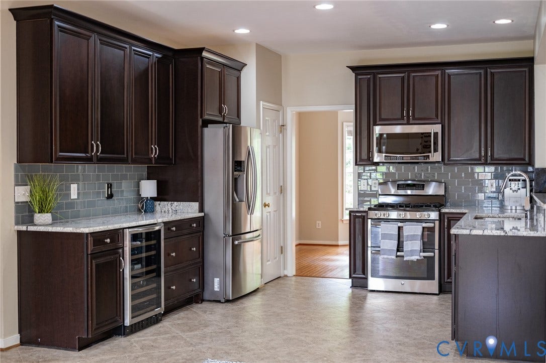 10517 Park Tree Place, Mountain Glen/ Glen Allen, Glen Allen, VA 23060 Kitchen featuring dark wood cabinetry, light-toned countertops, subway tile backsplash, stainless steel appliances, and a built-in beverage cooler