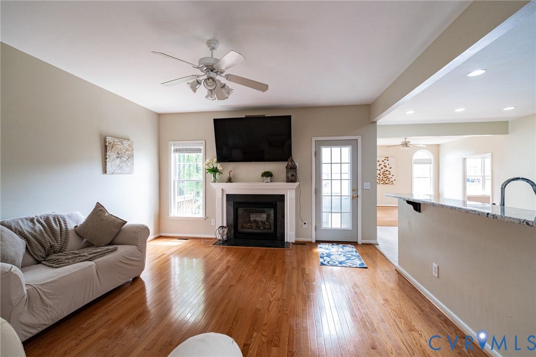 10517 Park Tree Place, Mountain Glen/ Glen Allen, Glen Allen, VA 23060 Living area featuring wood-finish flooring, a white ceiling fan, and a fireplace with a black surround and white mantel