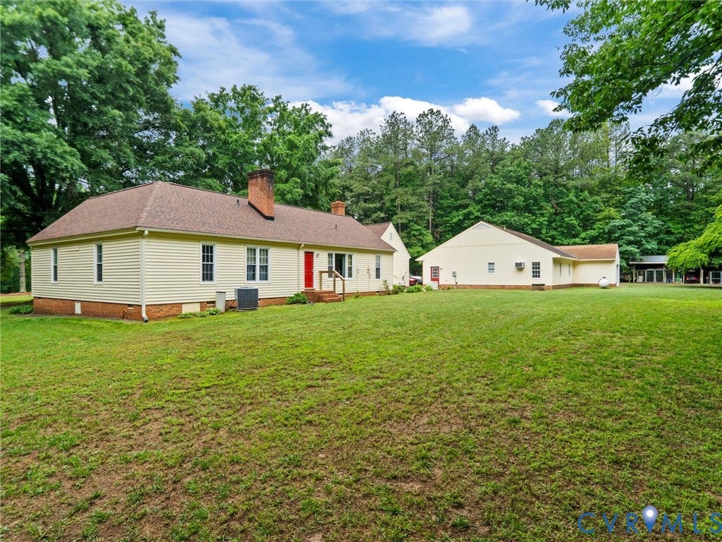 3420 Goodwyn Road, Powhatan, VA 23139 Expansive green lawn surrounding a light yellow sided structure with a brown shingle roof and a red entry door