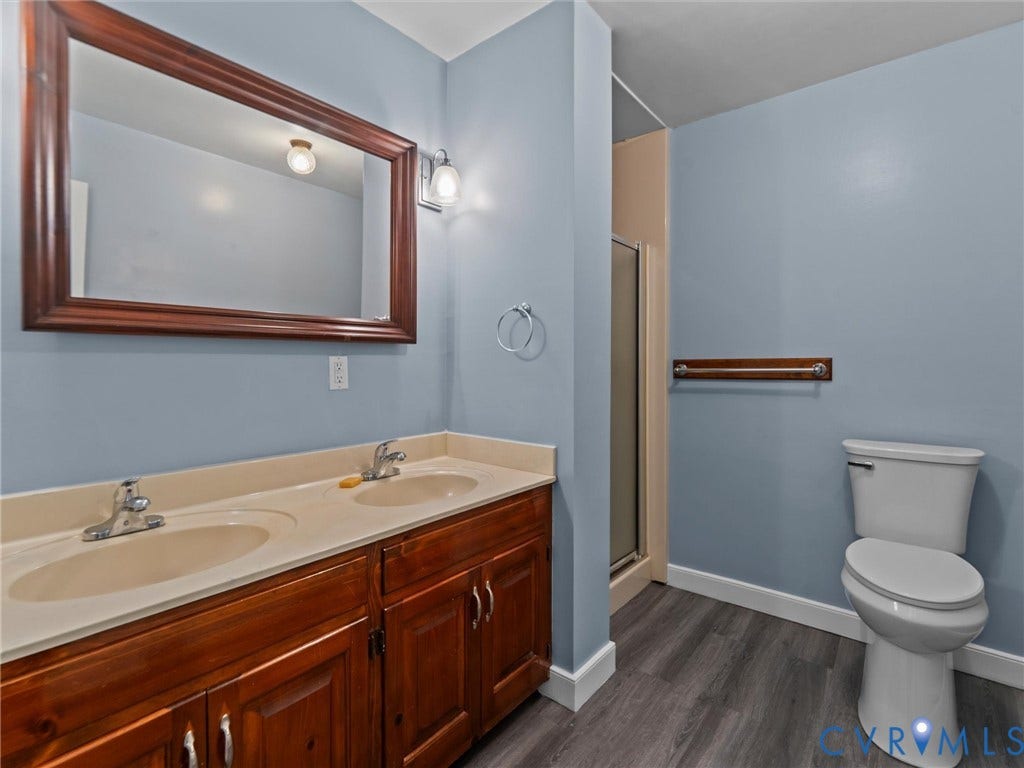3420 Goodwyn Road, Powhatan, VA 23139 Bathroom featuring a dual vanity with a light-colored countertop, wood-finish cabinetry, and a framed mirror
