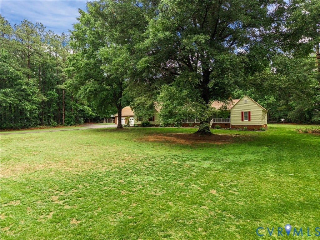 3420 Goodwyn Road, Powhatan, VA 23139 Expansive green lawn with mature trees and a detached structure featuring red shutters, a porch, and a light-colored exterior