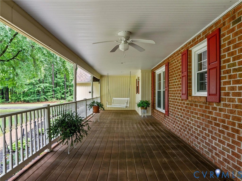 3420 Goodwyn Road, Powhatan, VA 23139 Expansive covered front porch featuring wood-finish flooring, a white baluster railing, and a beadboard ceiling with a ceiling fan
