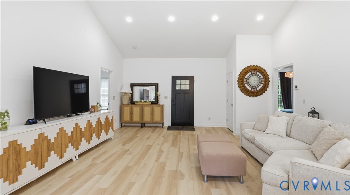 2406 Emanuel Church Road, Powhatan, VA 23139 Spacious living area featuring light wood-finish flooring, recessed lighting, a vaulted ceiling, a black paneled entry door, and white walls