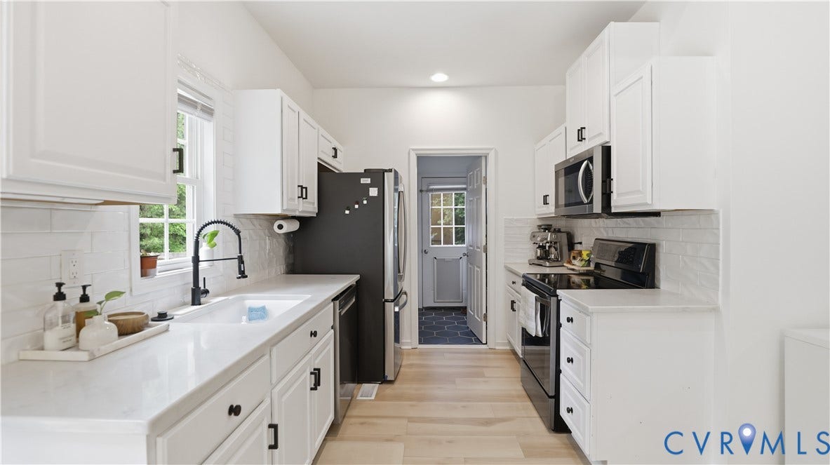 2406 Emanuel Church Road, Powhatan, VA 23139 Galley kitchen featuring white cabinetry, light countertops, subway tile backsplash, stainless steel appliances, and wood-finish flooring