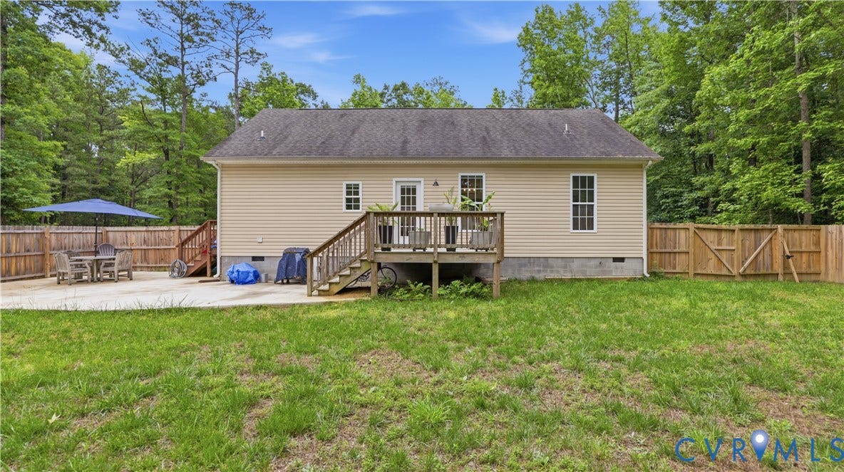2406 Emanuel Church Road, Powhatan, VA 23139 Rear exterior featuring a wood-plank deck with stairs, beige siding, multiple windows, and a concrete patio