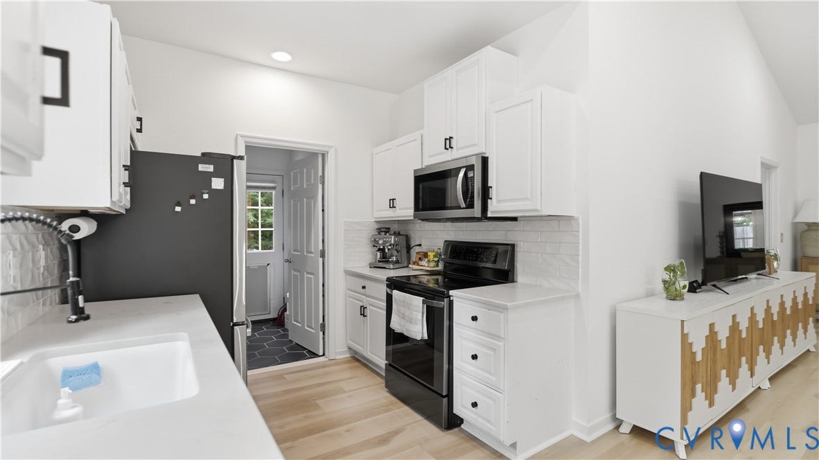 2406 Emanuel Church Road, Powhatan, VA 23139 Modern kitchen featuring white shaker cabinetry, stainless steel microwave, black electric range, and wood-finish flooring