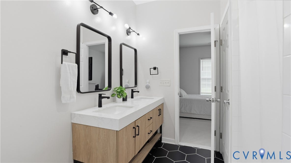2406 Emanuel Church Road, Powhatan, VA 23139 Double vanity with wood-finish cabinetry, black hardware, and an integrated white countertop