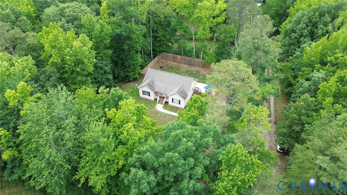 2406 Emanuel Church Road, Powhatan, VA 23139 Ranch-style home surrounded by mature trees, featuring a light-toned exterior, gabled roof, and a fenced backyard area