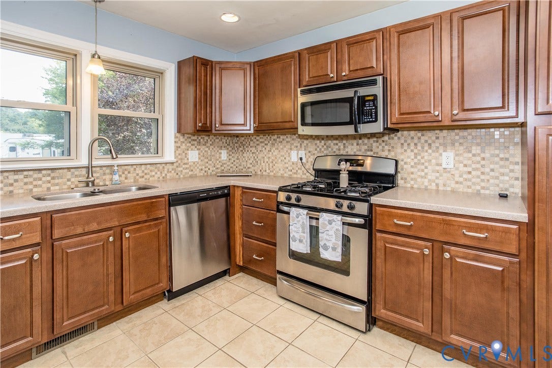 4512 Wraywood Avenue, Preston Place, Chester, VA 23831 Kitchen featuring wood cabinetry, stainless steel appliances, mosaic tile backsplash, a double basin sink, and tile flooring