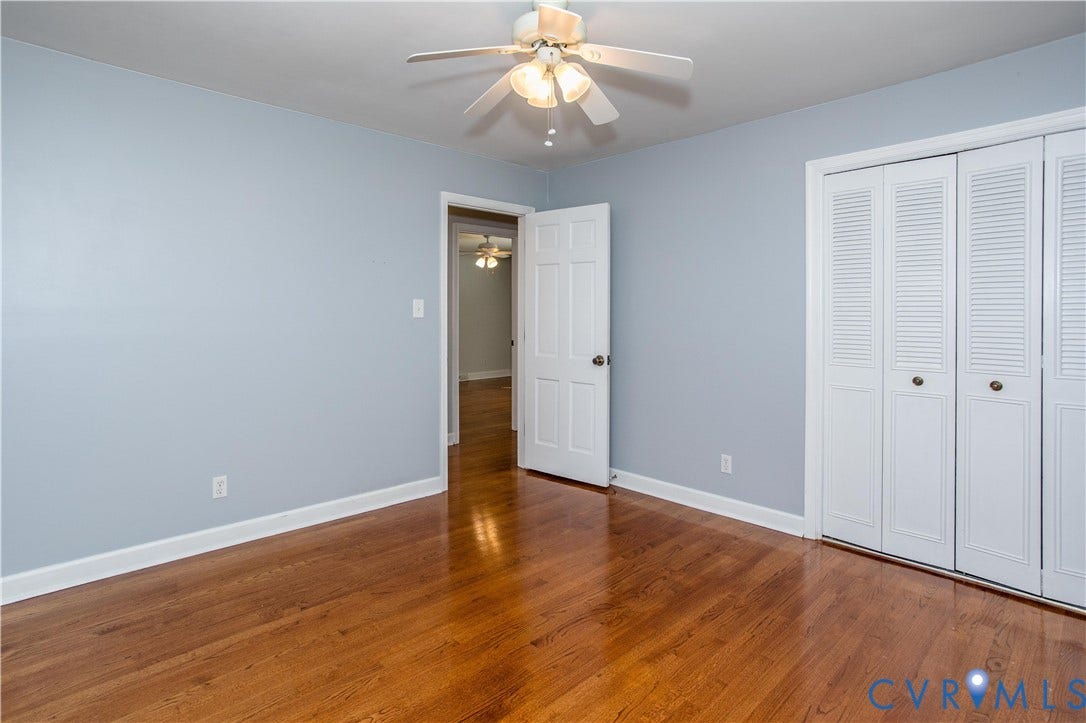 4512 Wraywood Avenue, Preston Place, Chester, VA 23831 Wood-finish flooring, light blue wall paint, white trim, white louvered bifold closet doors, and a ceiling fan with integrated lighting