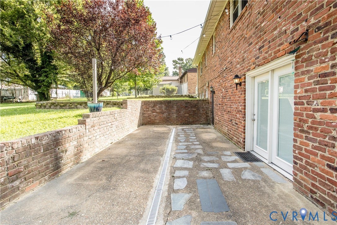 4512 Wraywood Avenue, Preston Place, Chester, VA 23831 Brick exterior with white double doors, featuring an exterior wall sconce, and a concrete patio with stone accents