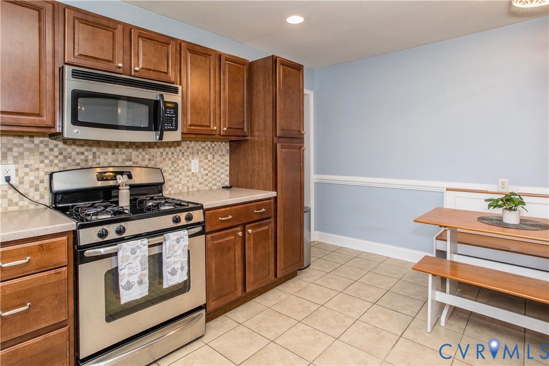 4512 Wraywood Avenue, Preston Place, Chester, VA 23831 Wood-finish cabinetry, stainless steel appliances, mosaic tile backsplash, light-toned countertops, and tiled flooring