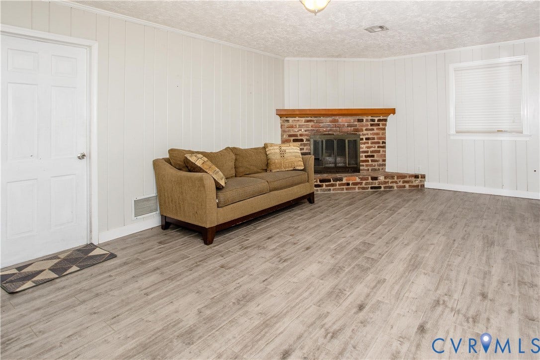 4512 Wraywood Avenue, Preston Place, Chester, VA 23831 Wood-finish flooring, brick-surround fireplace with wood mantel, paneled walls, ceiling-mounted light fixture, and white window blinds