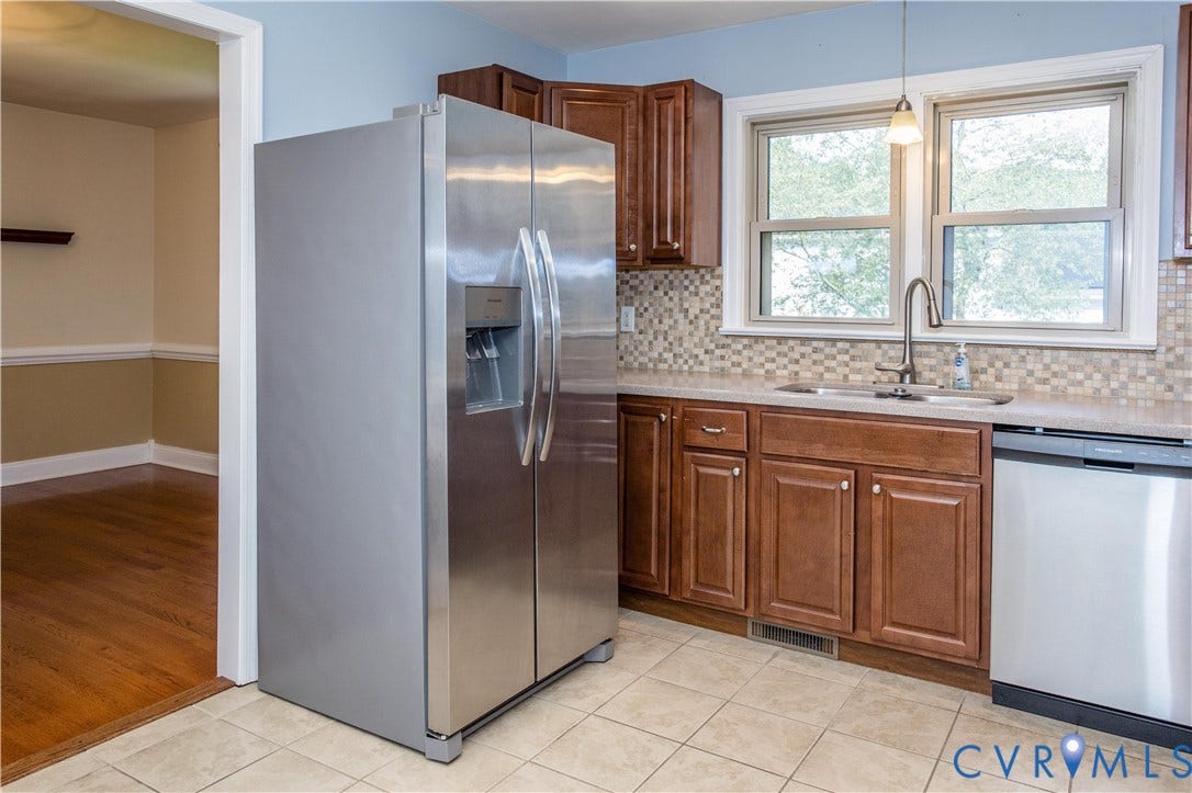 4512 Wraywood Avenue, Preston Place, Chester, VA 23831 Stainless steel side-by-side refrigerator, under-mount sink with gooseneck faucet, light-toned tiled flooring, wood-finish cabinetry, and a mosaic tile backsplash