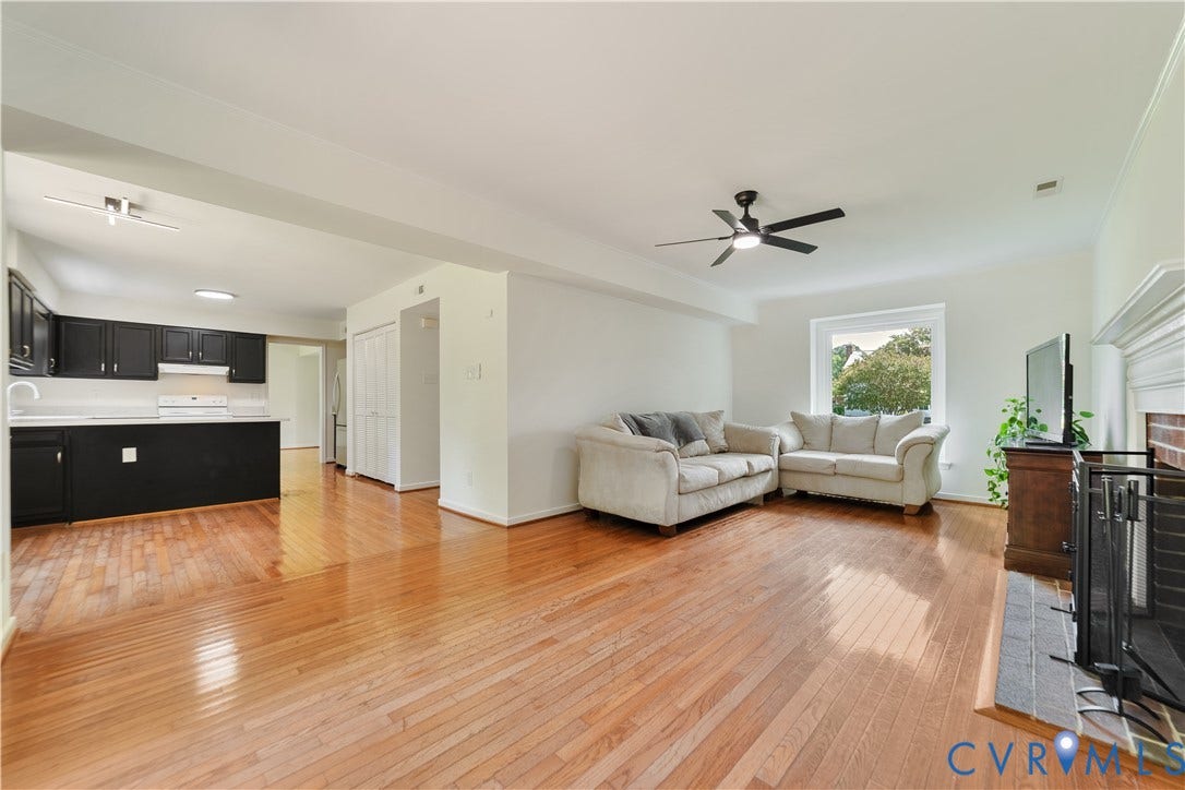 11060 Forest Trace Way, Forest Trace, Glen Allen, VA 23059 Hardwood flooring throughout, a ceiling fan with integrated lighting, a functional fireplace with a brick surround, and a kitchen featuring black cabinetry and white countertops