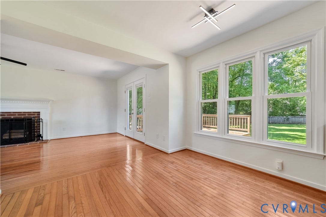 11060 Forest Trace Way, Forest Trace, Glen Allen, VA 23059 Hardwood flooring throughout, brick fireplace with white mantel, white double doors leading to an exterior deck, three large windows, and a modern ceiling fixture