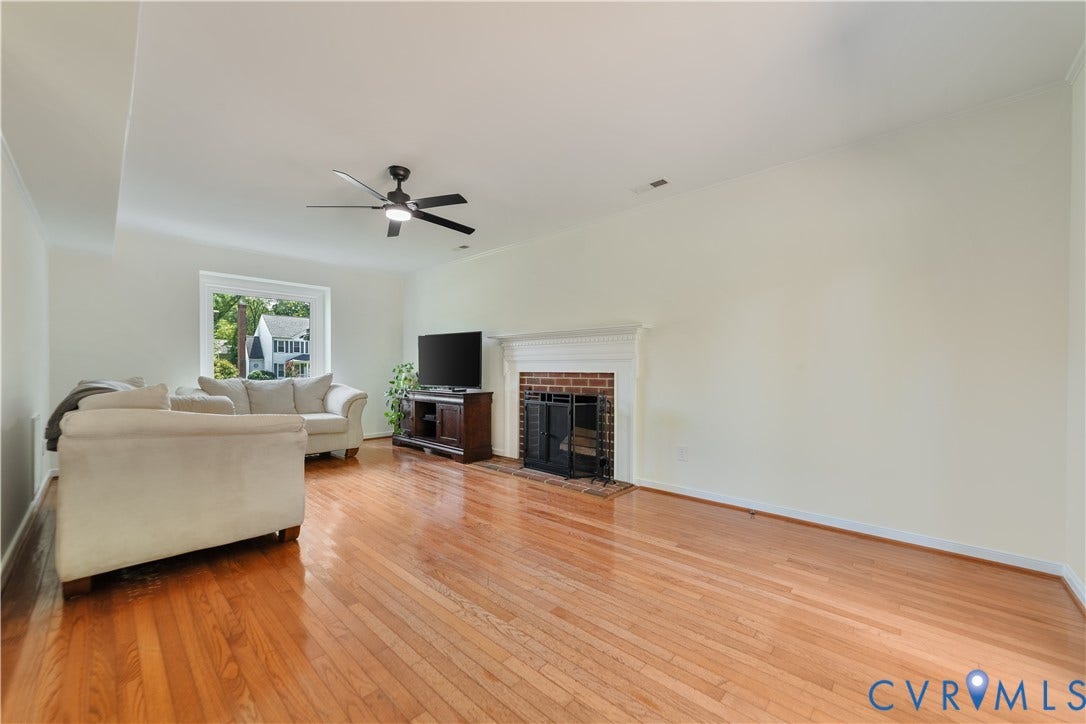 11060 Forest Trace Way, Forest Trace, Glen Allen, VA 23059 Spacious living area featuring light wood flooring, a white-mantled brick fireplace, and a ceiling fan