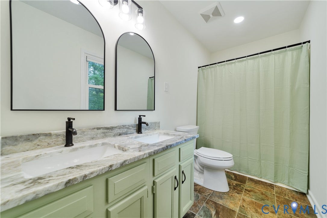 11060 Forest Trace Way, Forest Trace, Glen Allen, VA 23059 Dual arched mirrors over a double vanity with integrated sinks, a stone-finish countertop, and matte black fixtures