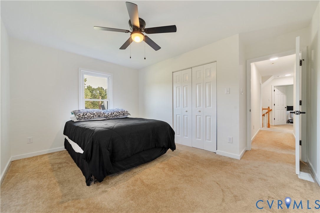 11060 Forest Trace Way, Forest Trace, Glen Allen, VA 23059 Spacious bedroom with neutral carpeting, ceiling fan with integrated lighting, dual closets with white six-panel doors, and a large window providing natural light