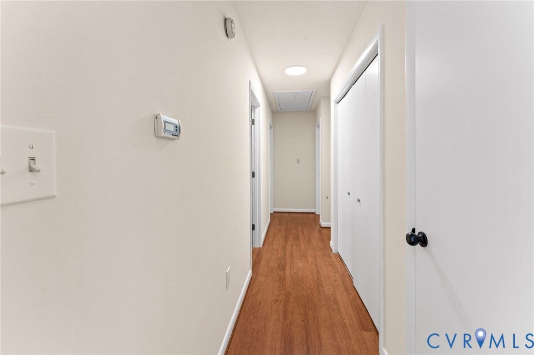 3020 Sand Hills Drive, Chester, VA 23831 Hallway featuring wood-finish flooring, light neutral wall paint, white trim, and white doors with dark hardware