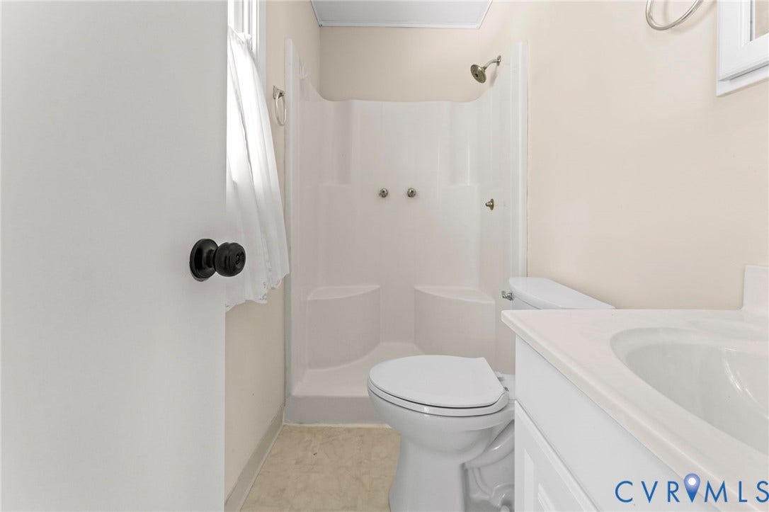 3020 Sand Hills Drive, Chester, VA 23831 Functional bathroom featuring a white vanity with integrated sink, a white toilet, and a stand-up shower with a single showerhead and separate controls